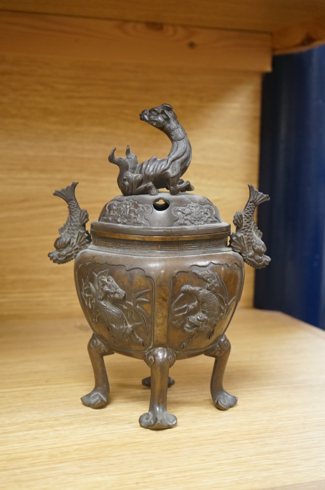 A Japanese bronze koro, raised on four feet with zoomorphic handles and knop, 23cm high